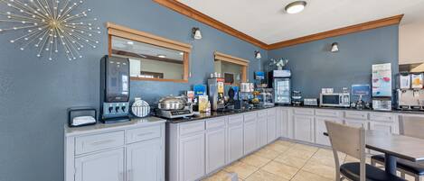 Una cocina moderna con una estación de café integrada, microondas y diversos alimentos.