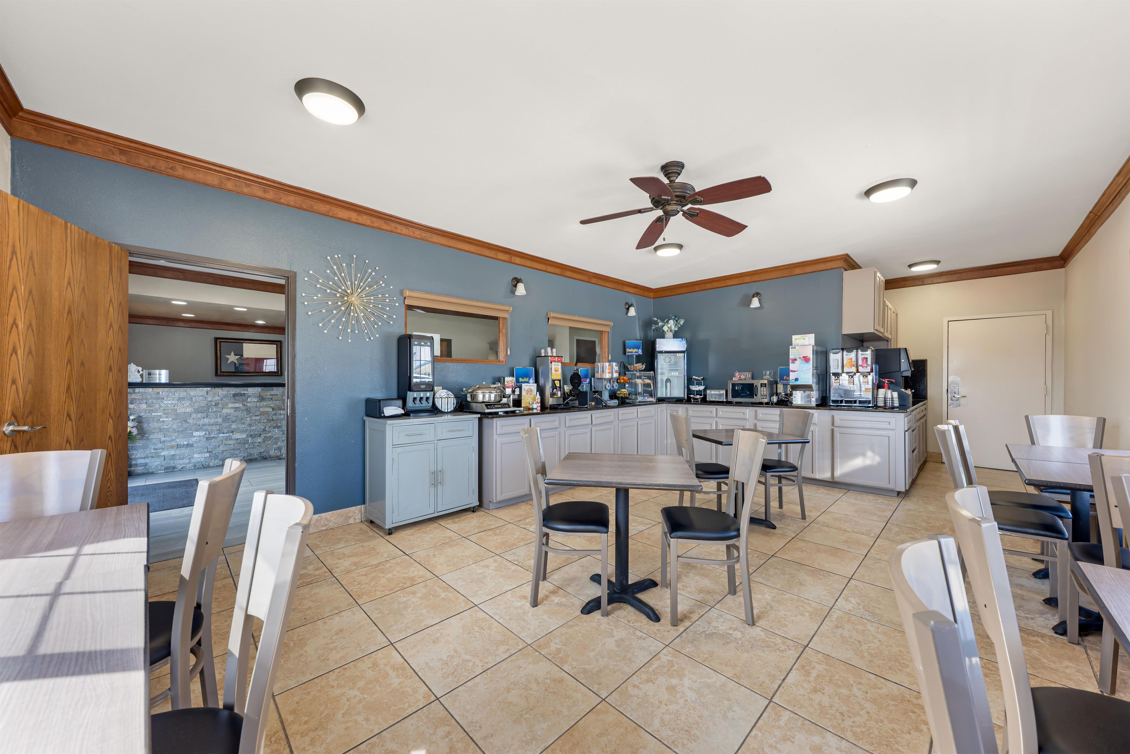 Cozinha moderna com área de jantar, com ventilador de teto, iluminação embutida e painel de backsplash de pedra.