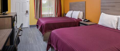 A hotel room with two beds, a desk with a computer, a TV, and a door.