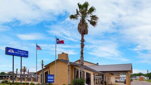 A hotel entrance with a sign for Americas Best Value Inn, a palm tree, and a clear sky. - Americas Best Value Inn West Columbia (West Columbia)