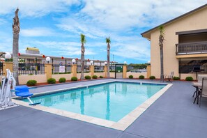 Una piscina al aire libre, sillones reclinables de piscina