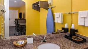 A bathroom with a granite countertop, a sink, a mirror, a hairdryer, a towel rack, and a basket with toiletries. - Americas Best Value Inn West Columbia (West Columbia)