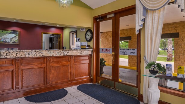 A reception area with a wooden counter, a clock, and a 'PUSH DOOR' sign. - Americas Best Value Inn West Columbia (West Columbia)