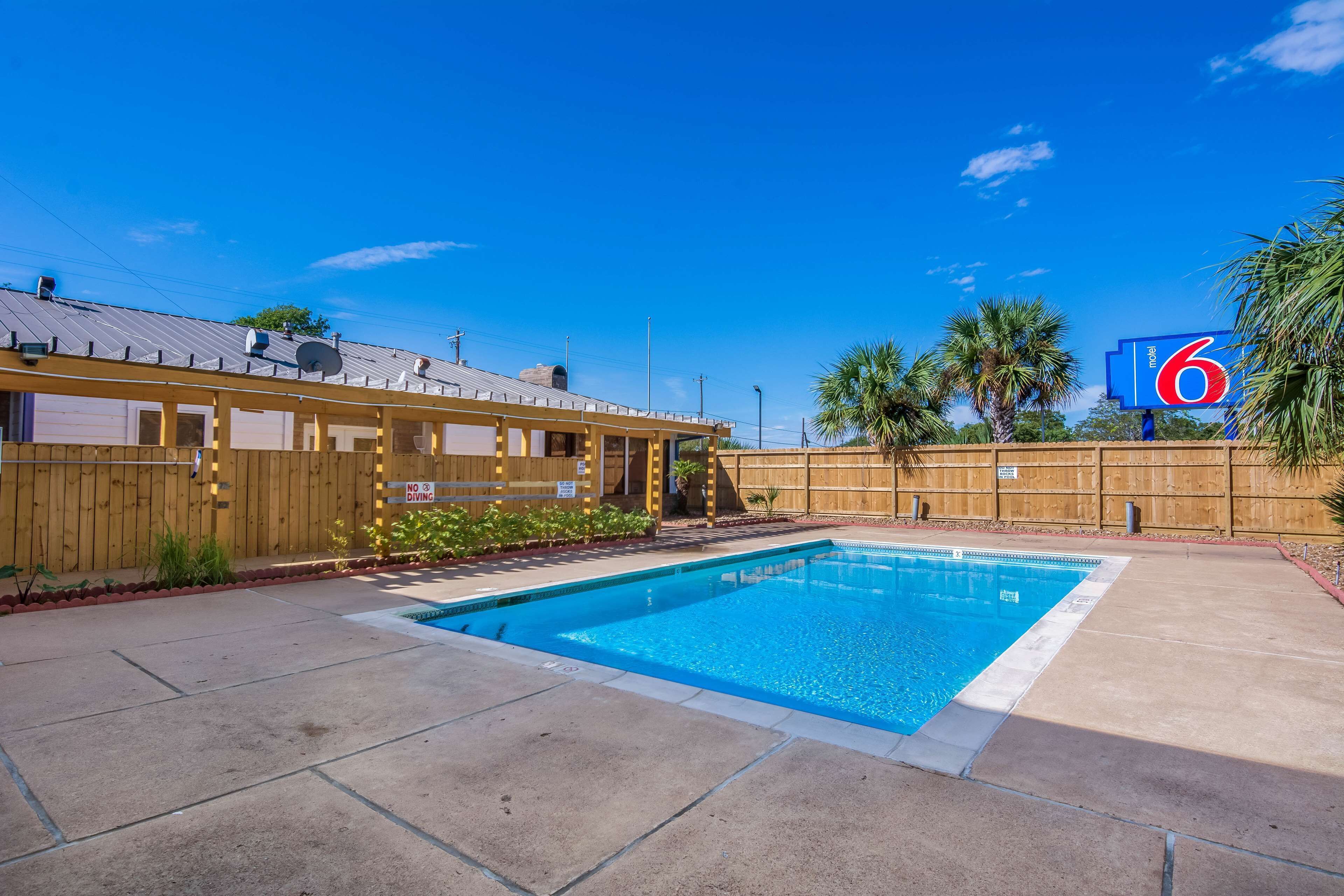 A swimming pool with a wooden fence and a sign indicating a no diving area.