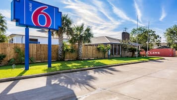 A motel sign with the number 6, a wooden fence, and a building with a sloped roof.