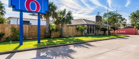A motel sign with the number 6, a wooden fence, and a building with a sloped roof.