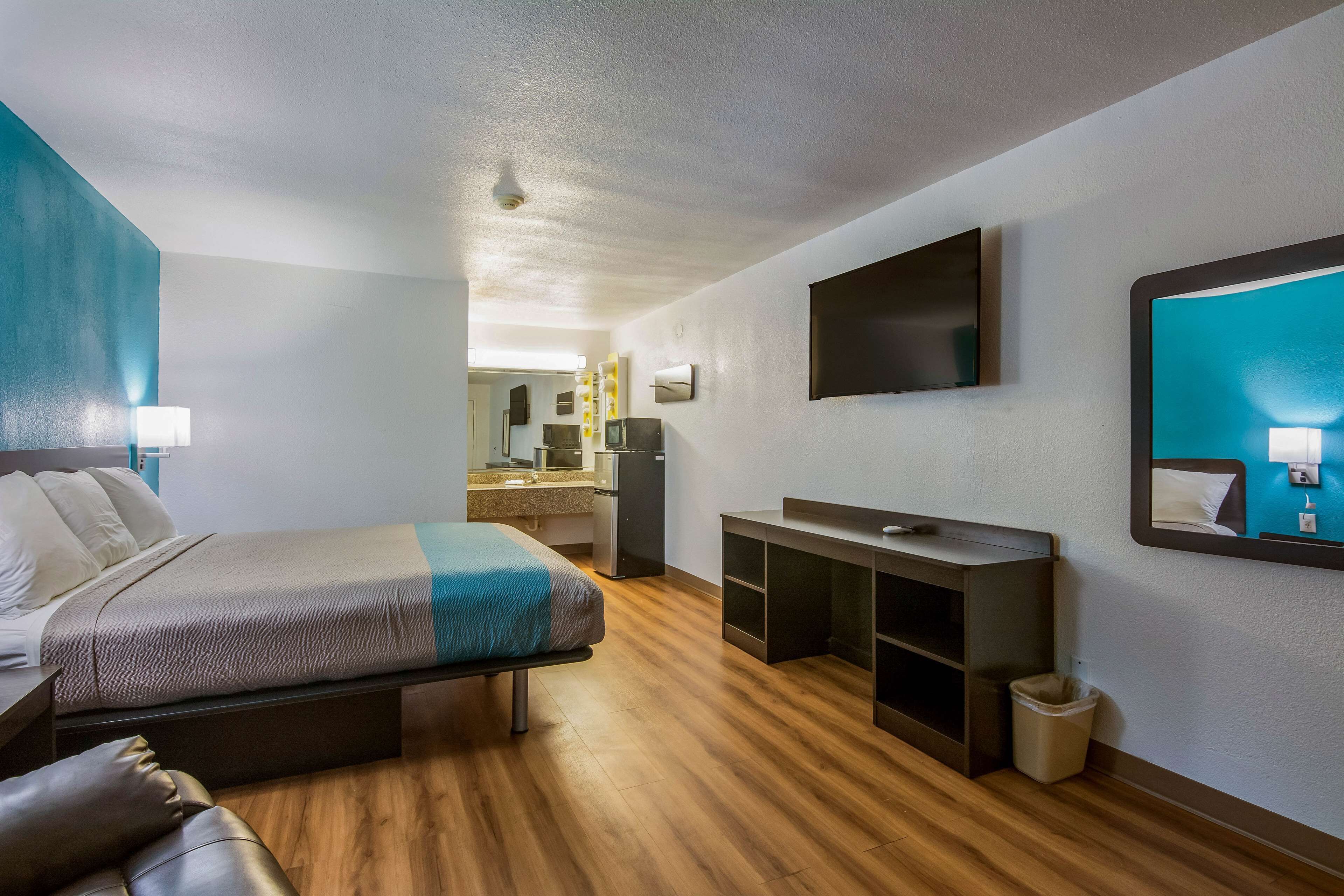 A hotel room with a bed, a desk, a TV, and a mirror.