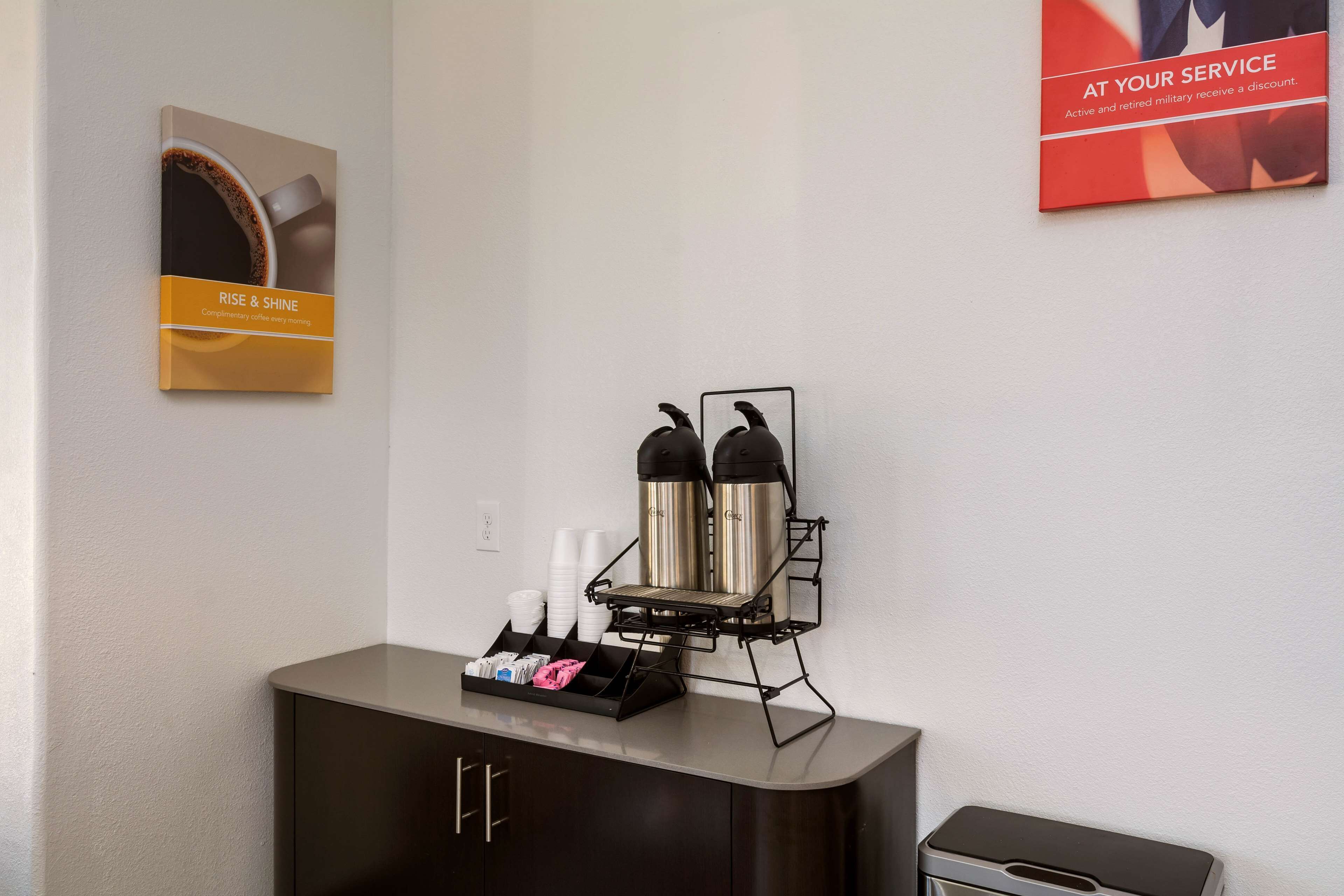 Uma estação de café com máquina de café, xícaras e bandeja de cápsulas.