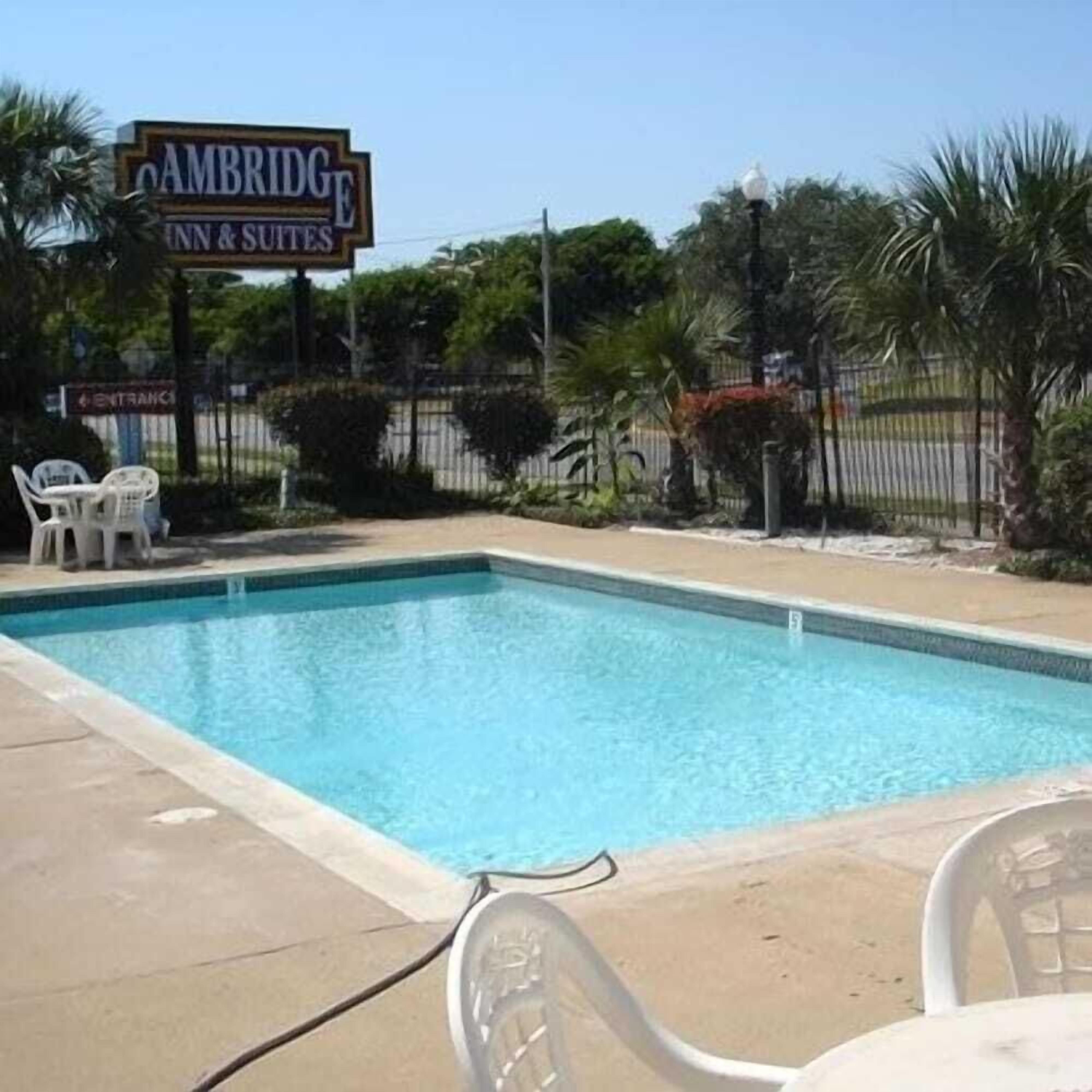 A swimming pool area with a sign for 'Cambridge Inn & Suites'.