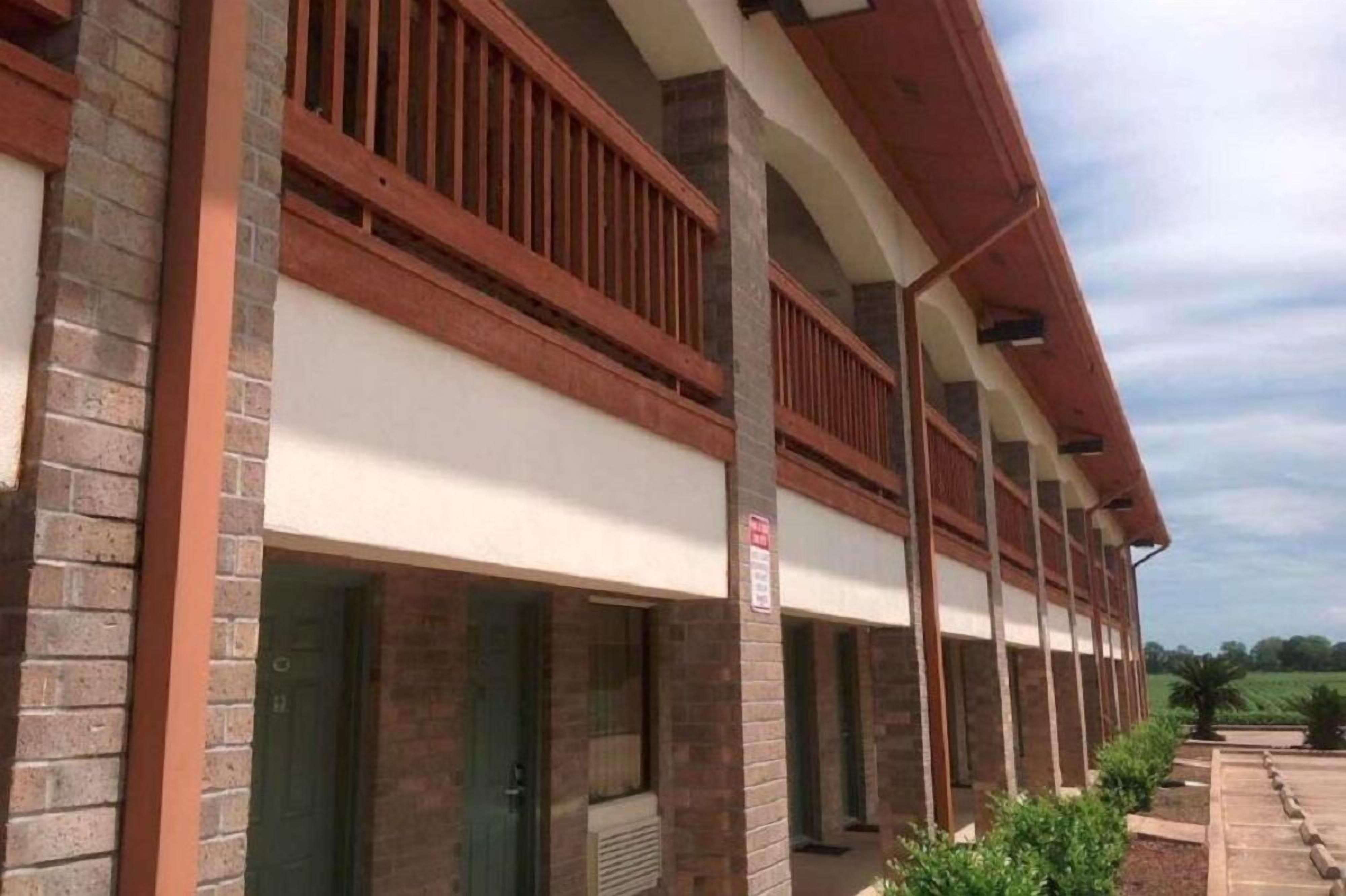A building with a brick facade, multiple balconies with wooden railings, and a covered walkway.