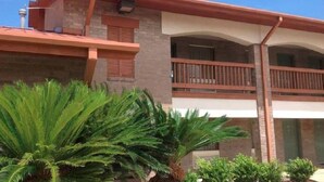 A two-story building with a balcony, brick walls, and a red roof.