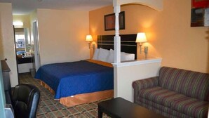 A hotel room with a bed, two bedside lamps, a sofa, a small table, and a patterned carpet.