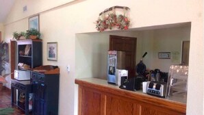 A kitchen area with a wooden counter, a refrigerator, a coffee maker, and a microwave.