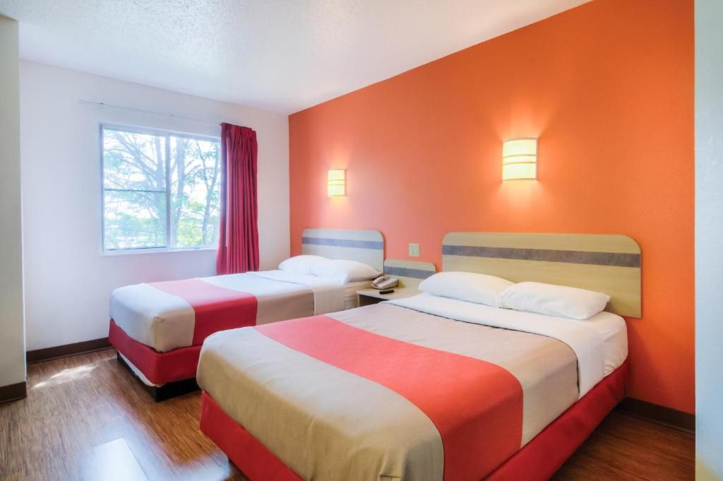 Habitación de hotel con dos camas, una ventana con vistas y dos lámparas fijadas a la pared.