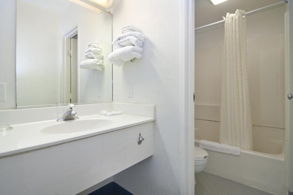 Un baño con lavamanos blanco, espejo y cortina de ducha.
