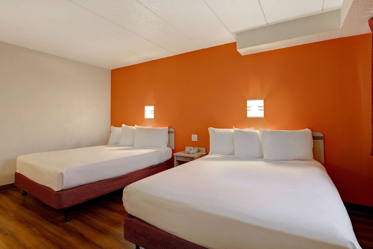Een hotelkamer met twee bedden, houten vloer en oranje wanden.