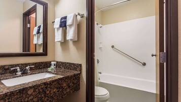 A bathroom with a granite countertop sink, a mirror, and a white toilet.