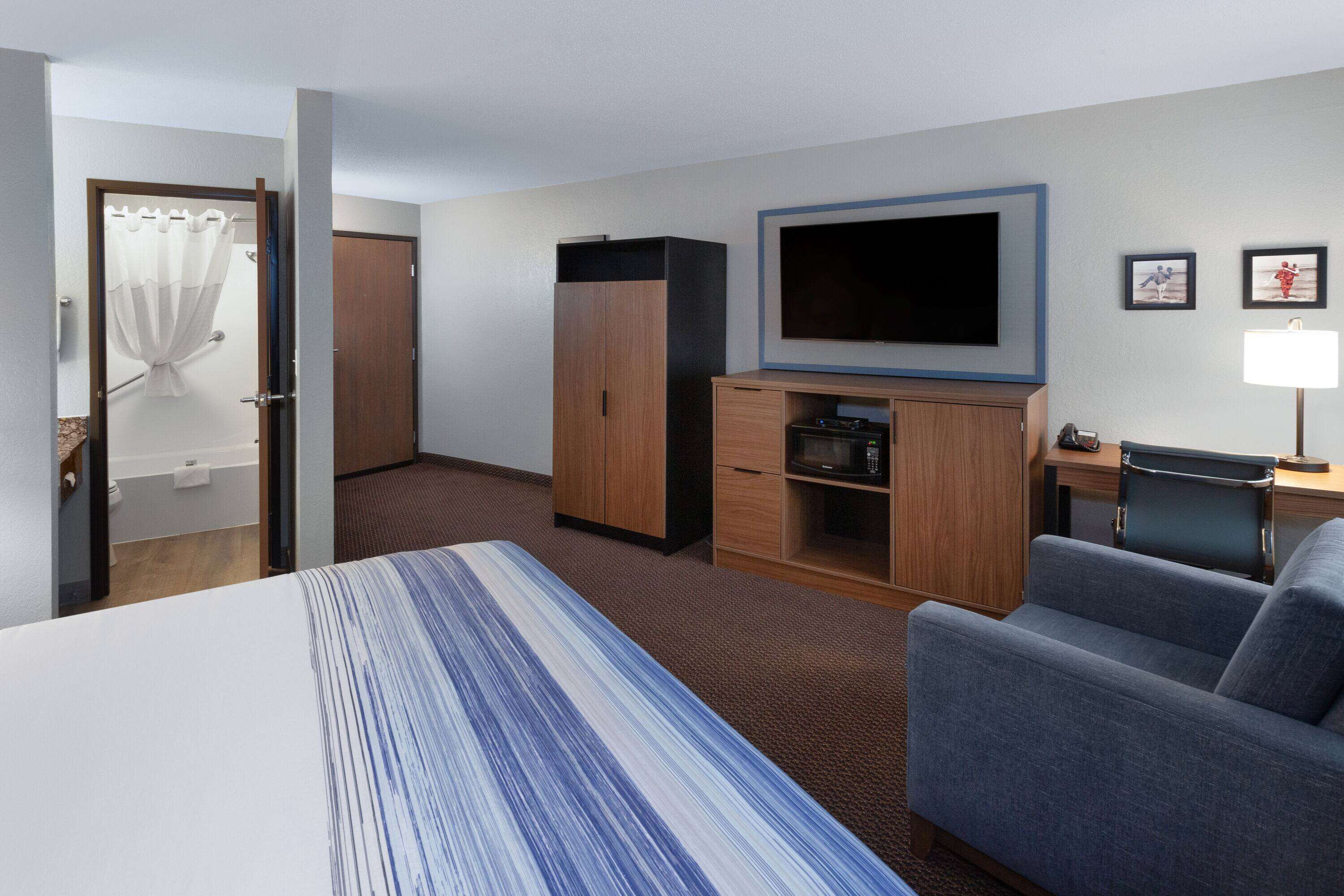 A hotel room with a bed, a TV, a desk, a chair, and a wardrobe.