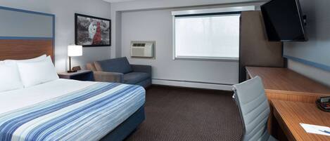 A hotel room with a bed, a desk, a chair, a television, a window, and a picture on the wall.