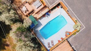 An aerial view of a pool area with a wooden deck, lounge chairs, and a covered seating area. - Salida Inn & Monarch Suites (Salida)