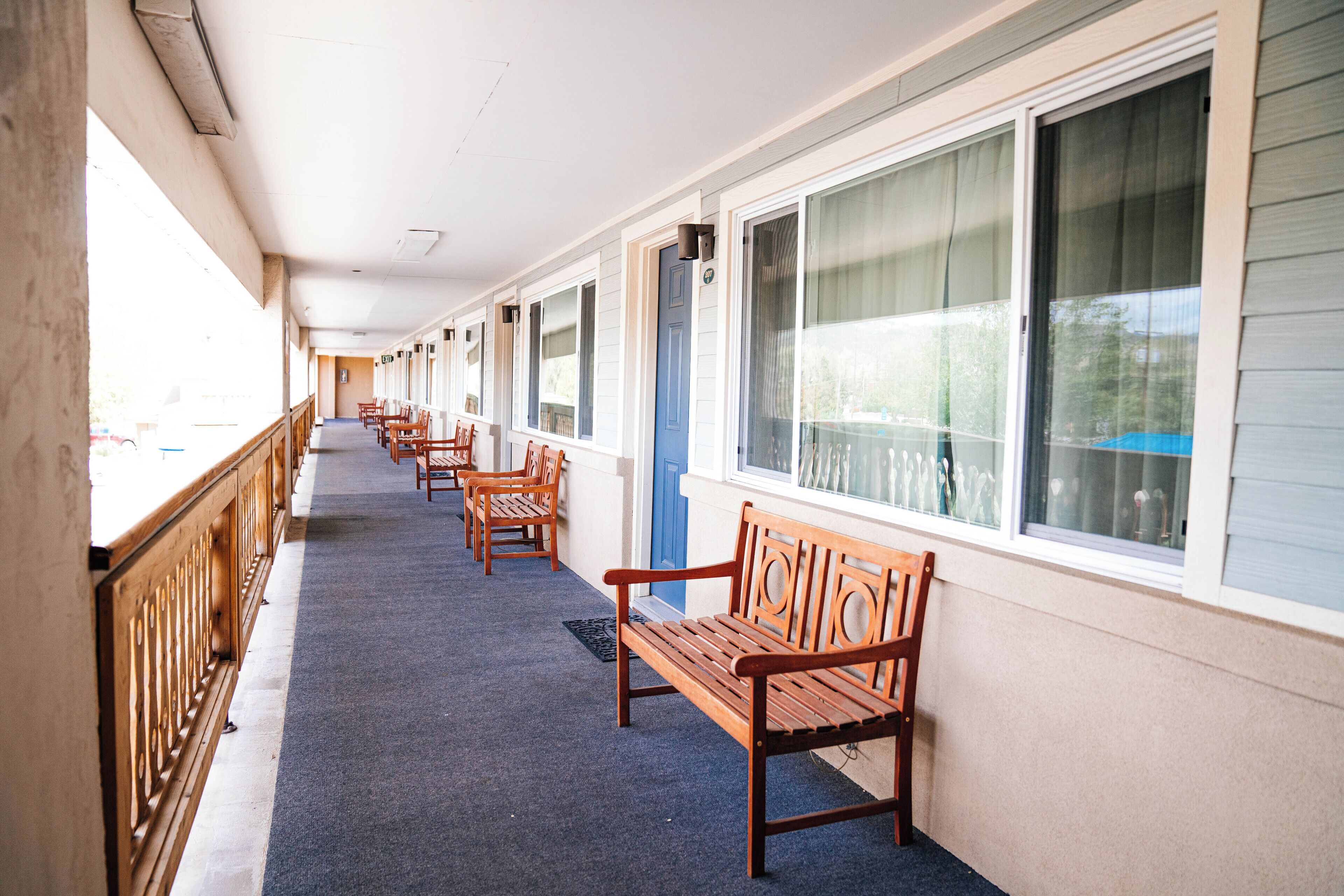 A covered corridor with wooden benches and large windows.