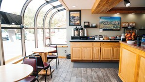 A restaurant with a large window, wooden cabinets, and a counter with food items. - Salida Inn & Monarch Suites (Salida)