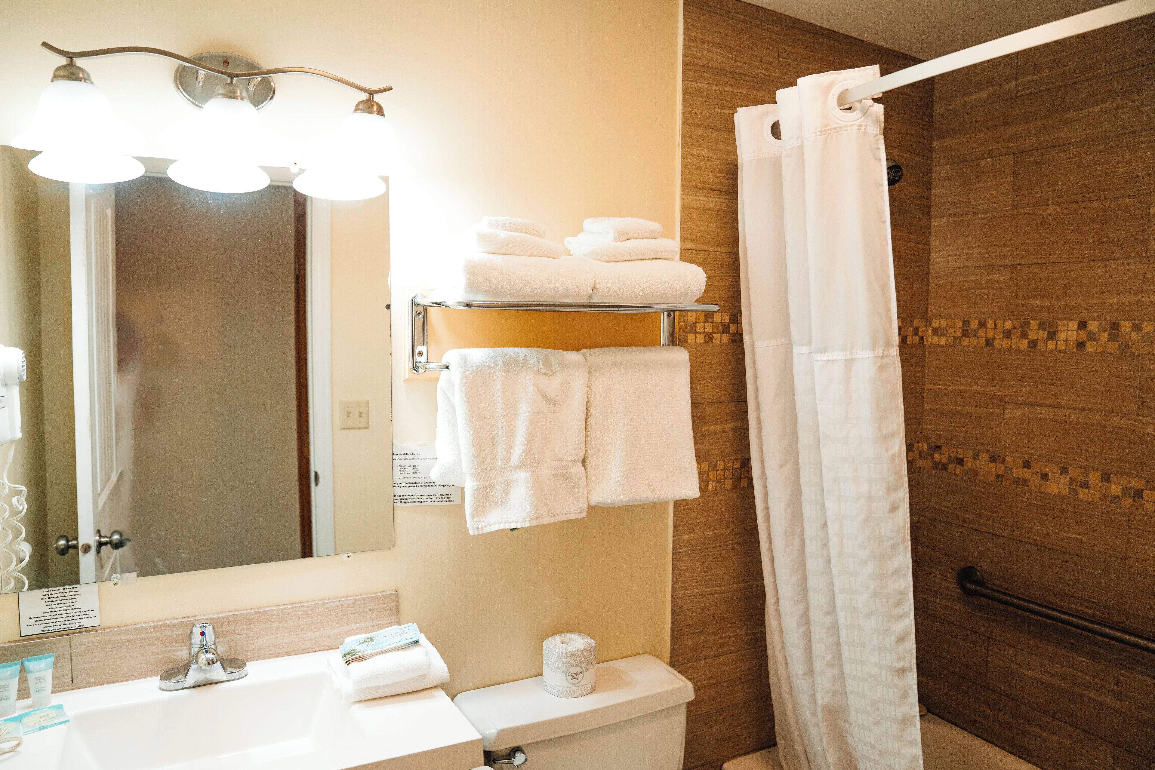 Un baño con lavamanos, espejo, toallero y cortina de ducha.