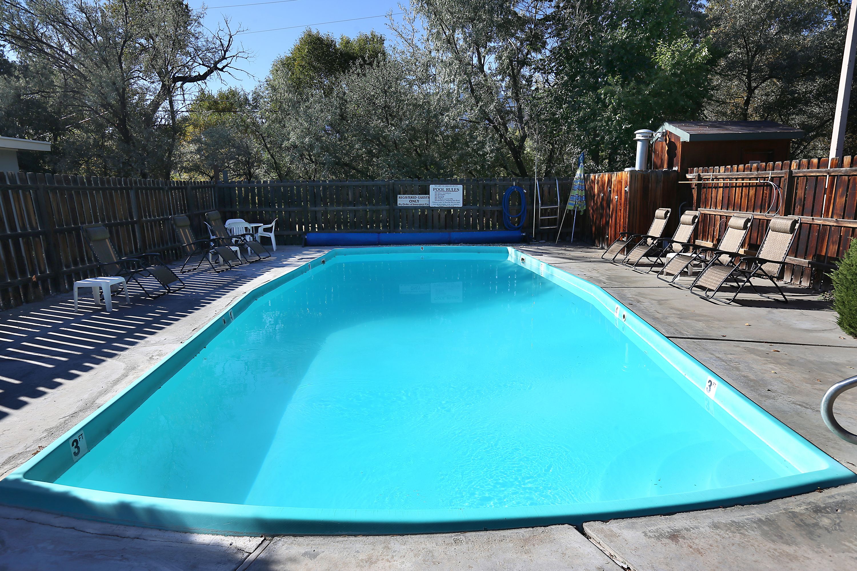 Une piscine rectangulaire dotée d’une terrasse en bois et de chaises longues.