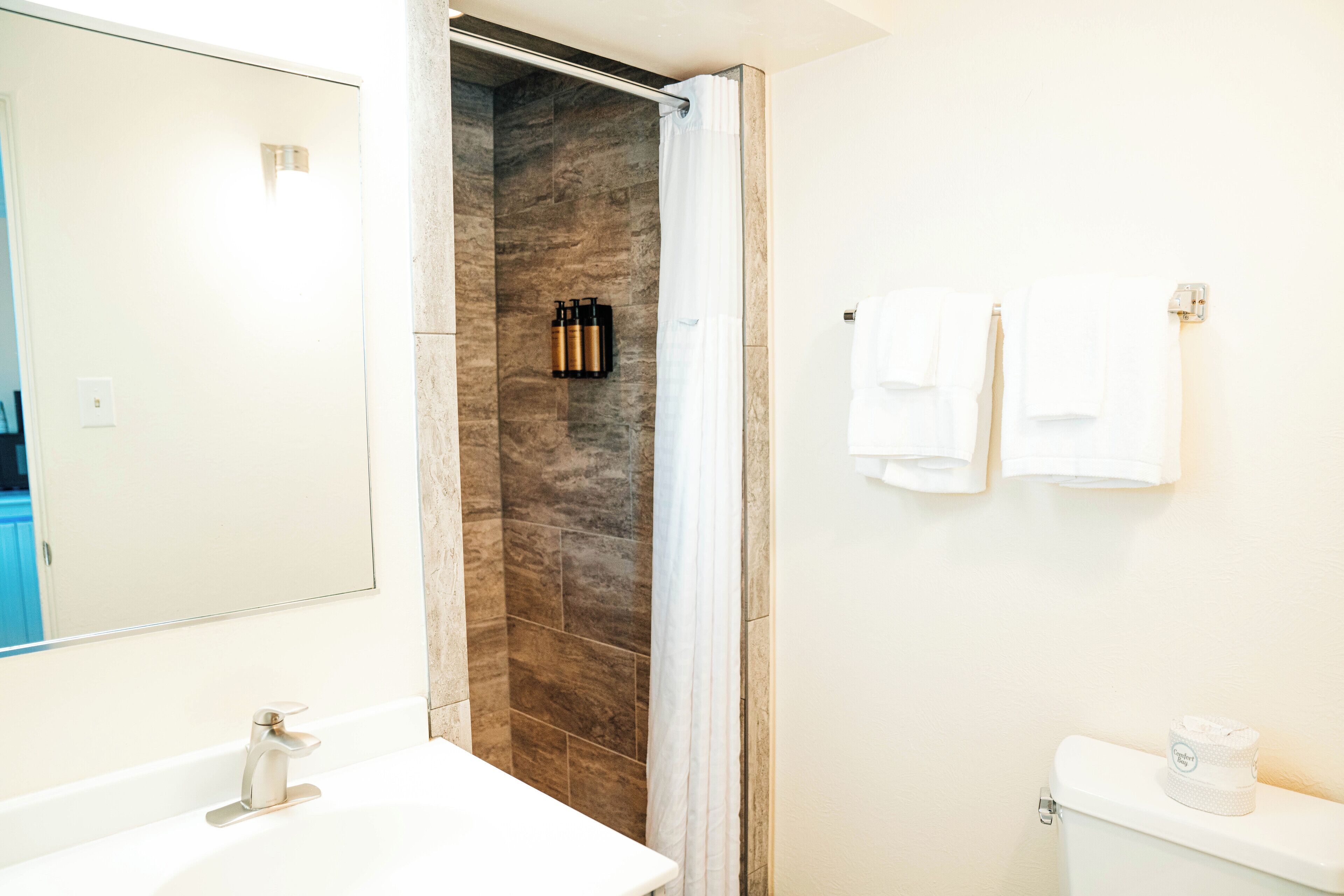 A modern bathroom with a shower, a sink, and a toilet.