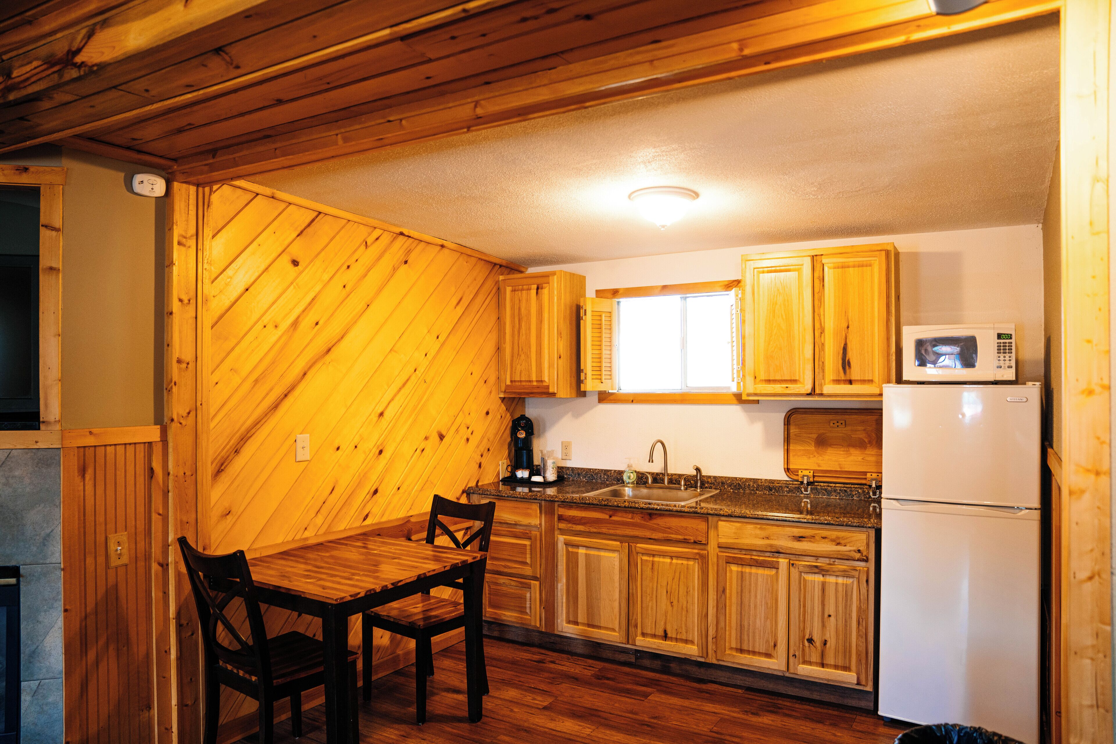 A kitchen with wooden cabinets, a dining table, and chairs.