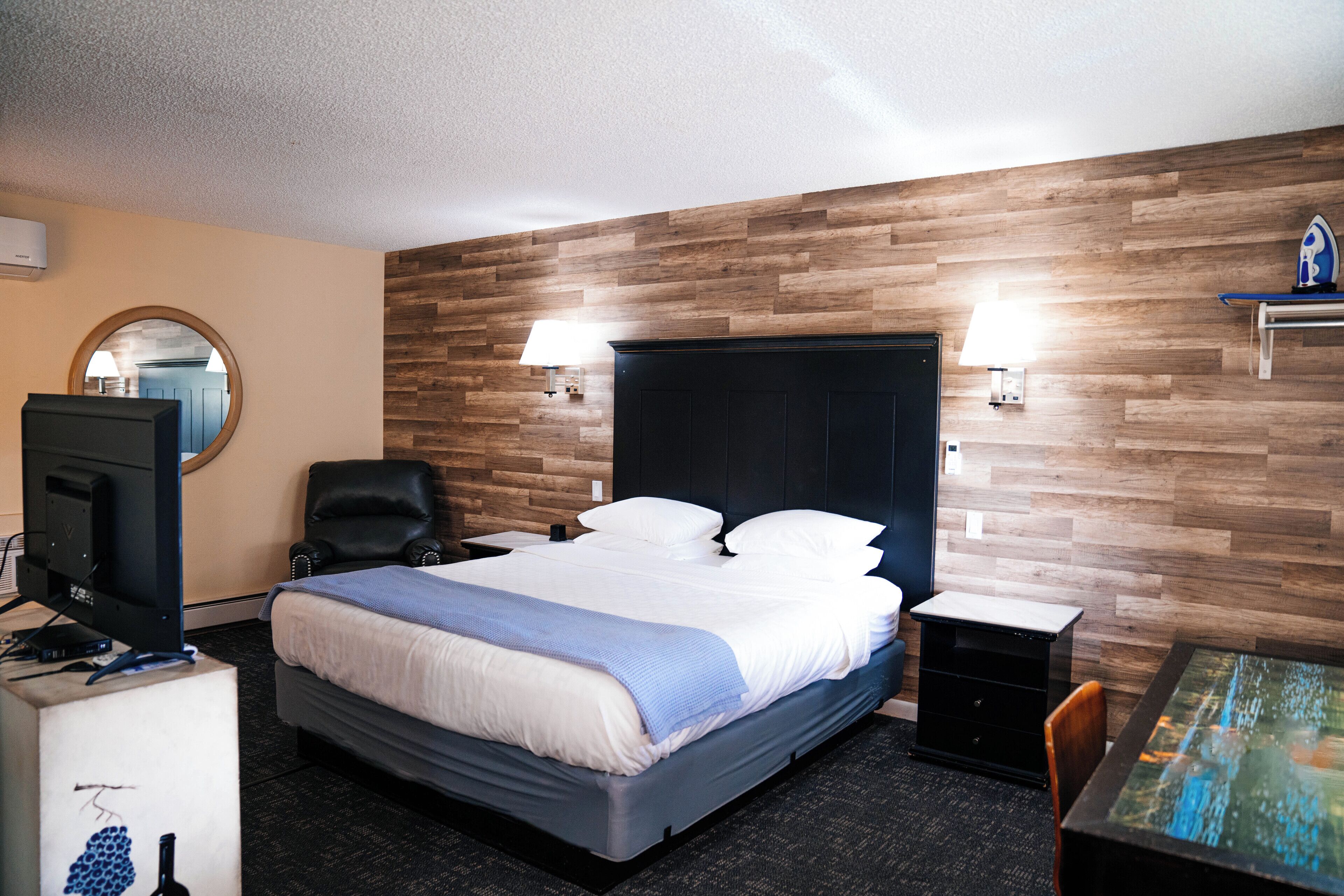 Een hotelkamer met een bed, een bureau, een stoel, een televisie en een lamp.