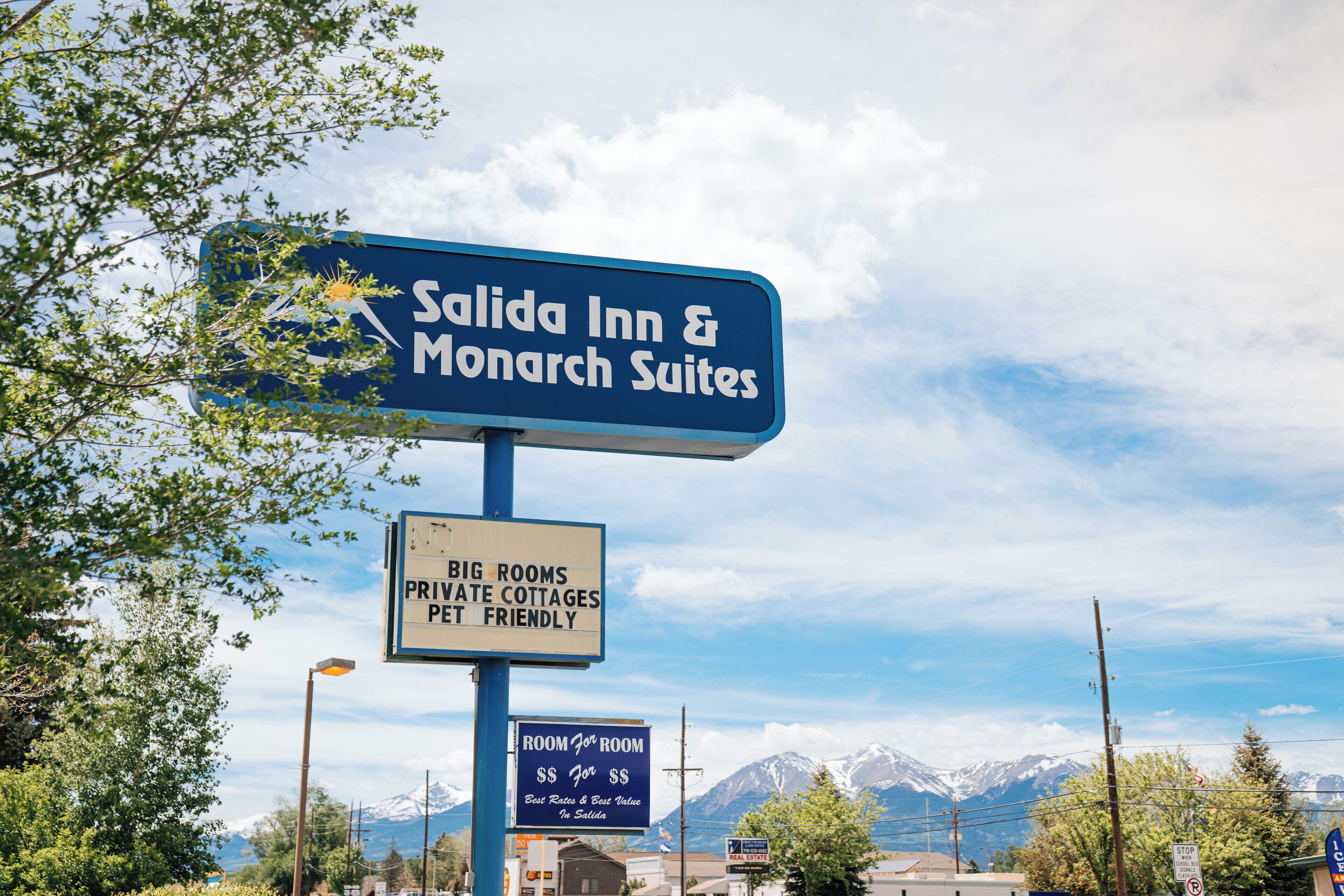 Un cartel de Salida Inn & Monarch Suites que anuncia habitaciones privadas, cabañas y alojamiento para mascotas.