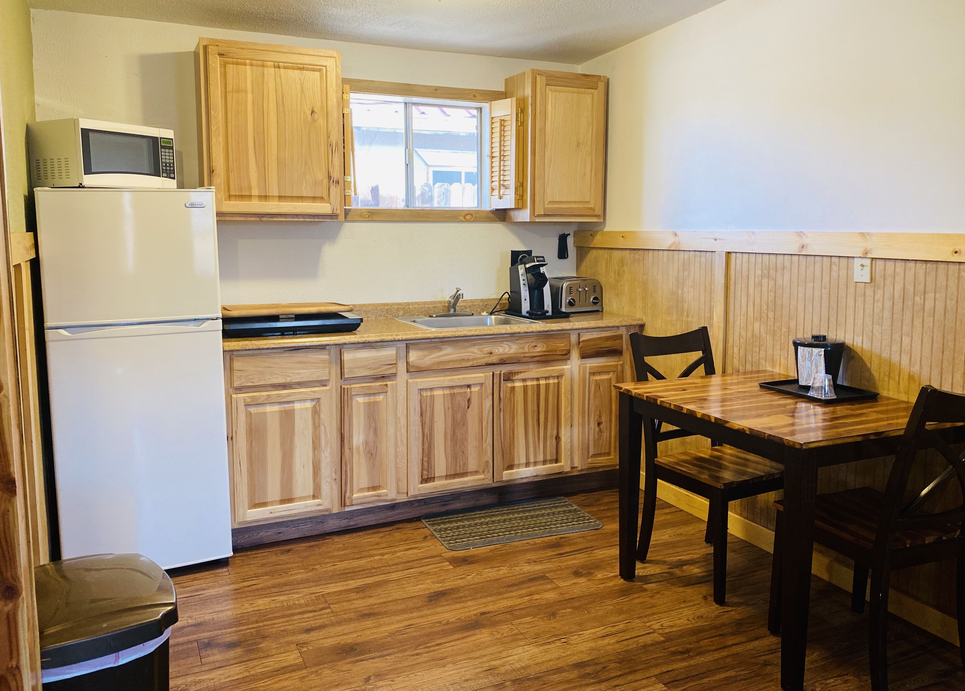 A compact kitchen with wooden cabinets, a microwave, a toaster, and a coffee maker.