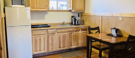 A compact kitchen with wooden cabinets, a microwave, a toaster, and a coffee maker.