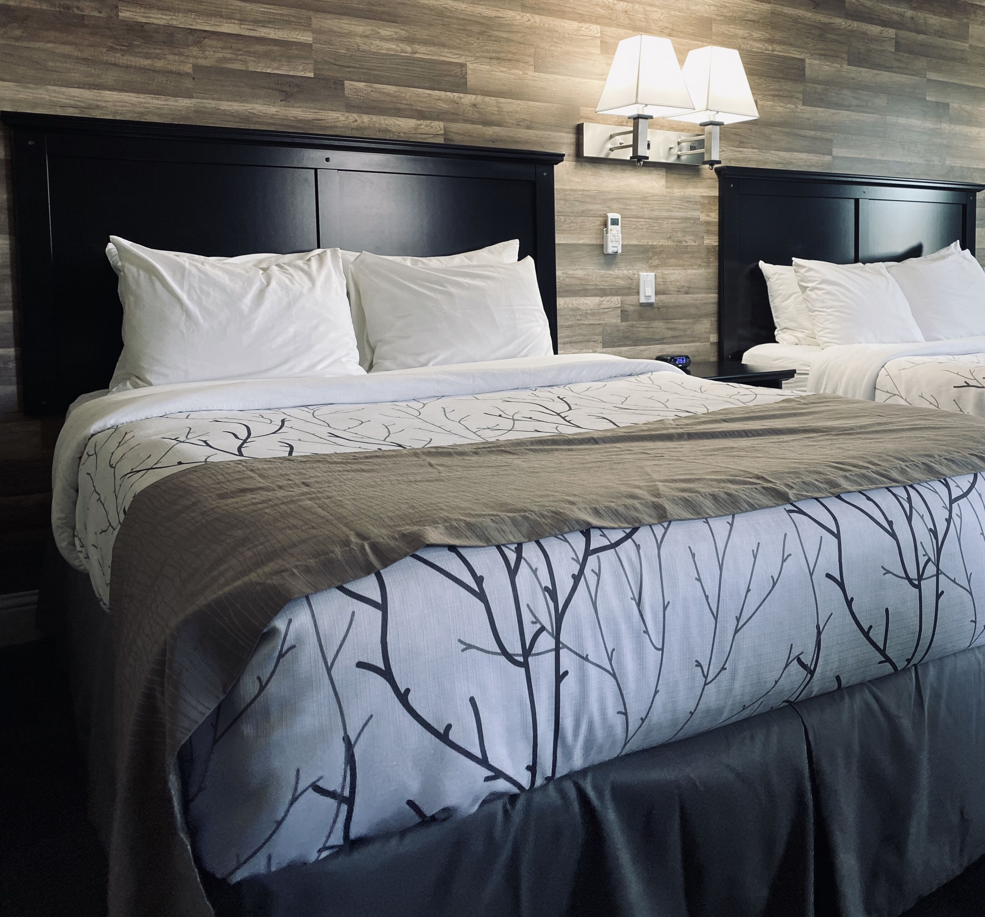 A hotel room with a large bed, dark headboard, and a wall-mounted lamp.