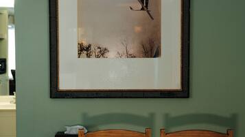 A framed picture of a person skiing on a mountain, a wooden table, and two wooden chairs.