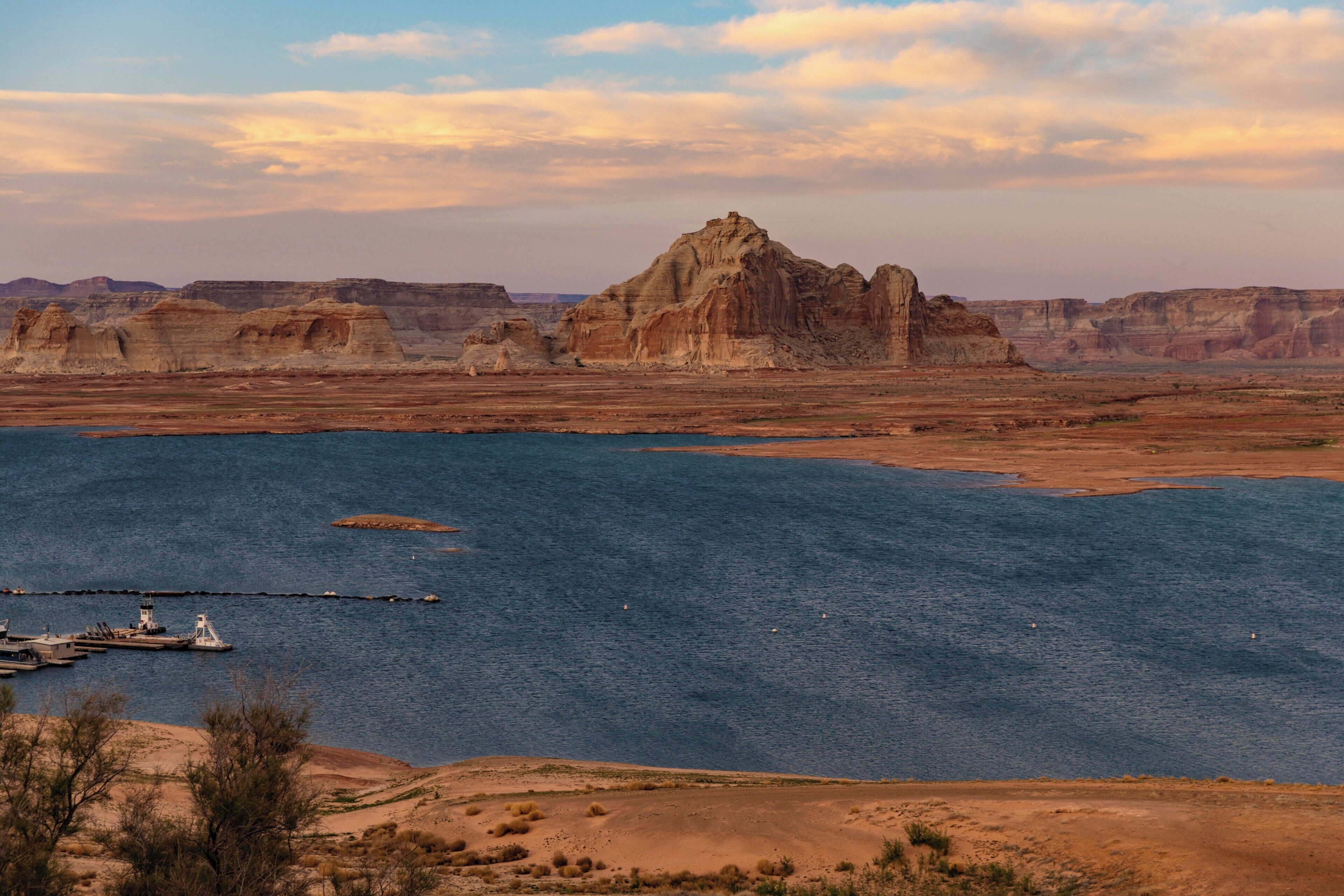Un paysage désertique avec une étendue d’eau importante, un quai et une formation rocheuse remarquable.