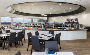 Un comedor moderno con un bufé central, ventanas amplias y vistas al paisaje.