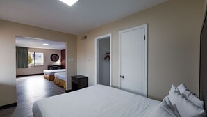 A hotel room with a large bed, a bedside table, a wardrobe, and a view of another room. - Super 8 by Wyndham Williams West Route 66/Grand Canyon Area (Williams)