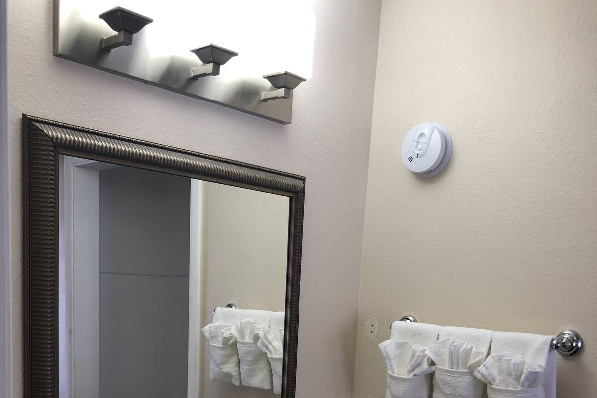 A bathroom with a large mirror, a sink, and towel racks.