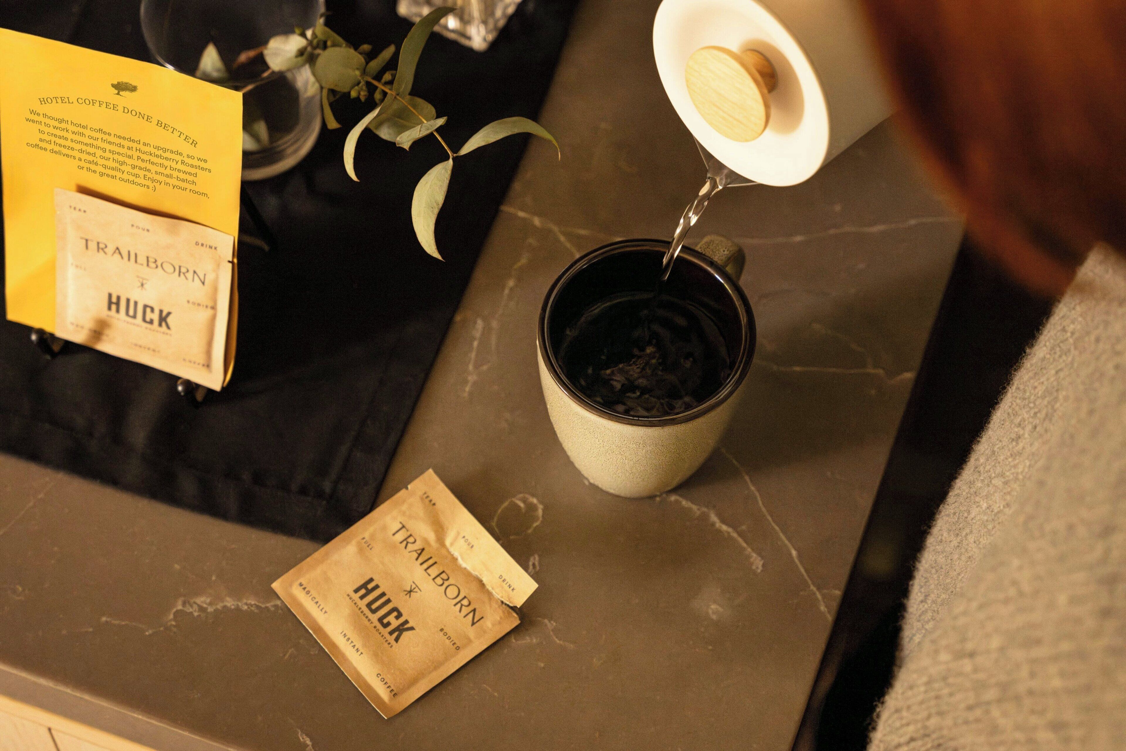 A coffee cup on a table with a packet of coffee and a sign about hotel coffee.