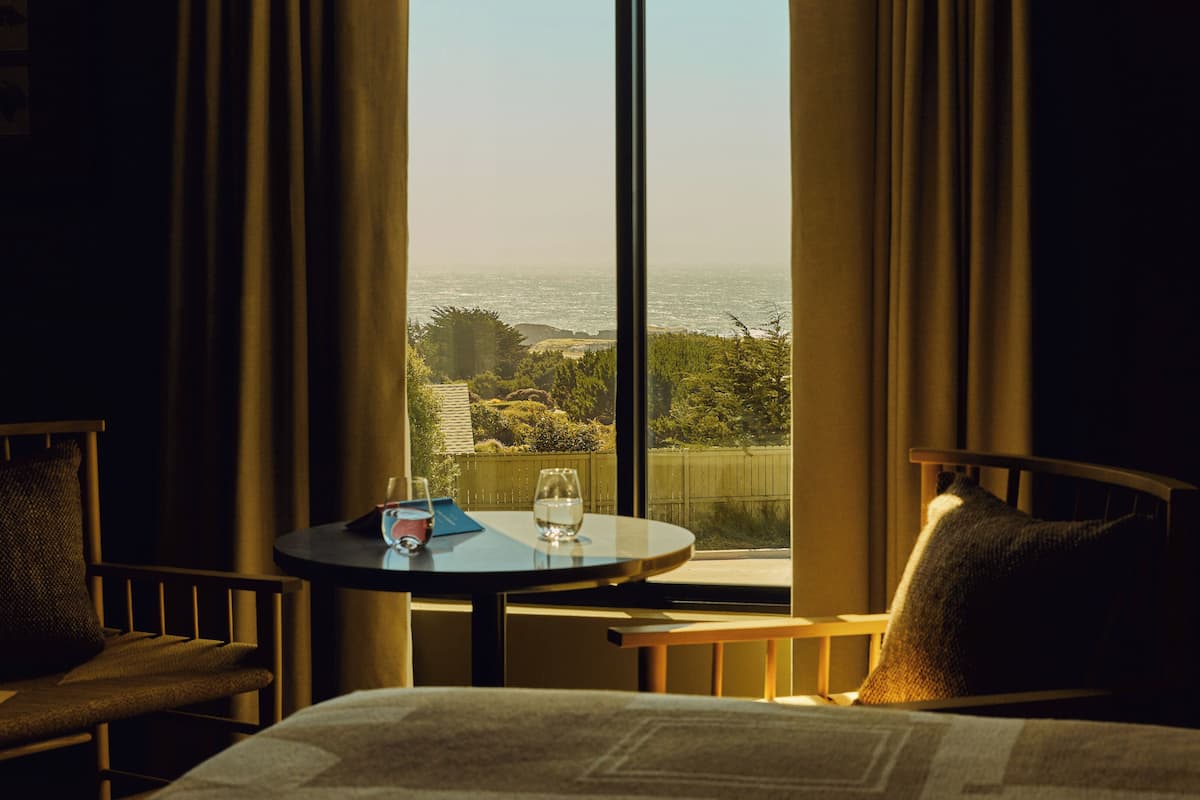 Une chambre d’hôtel avec un lit, une table sur laquelle se trouve un verre d’eau et une chaise.