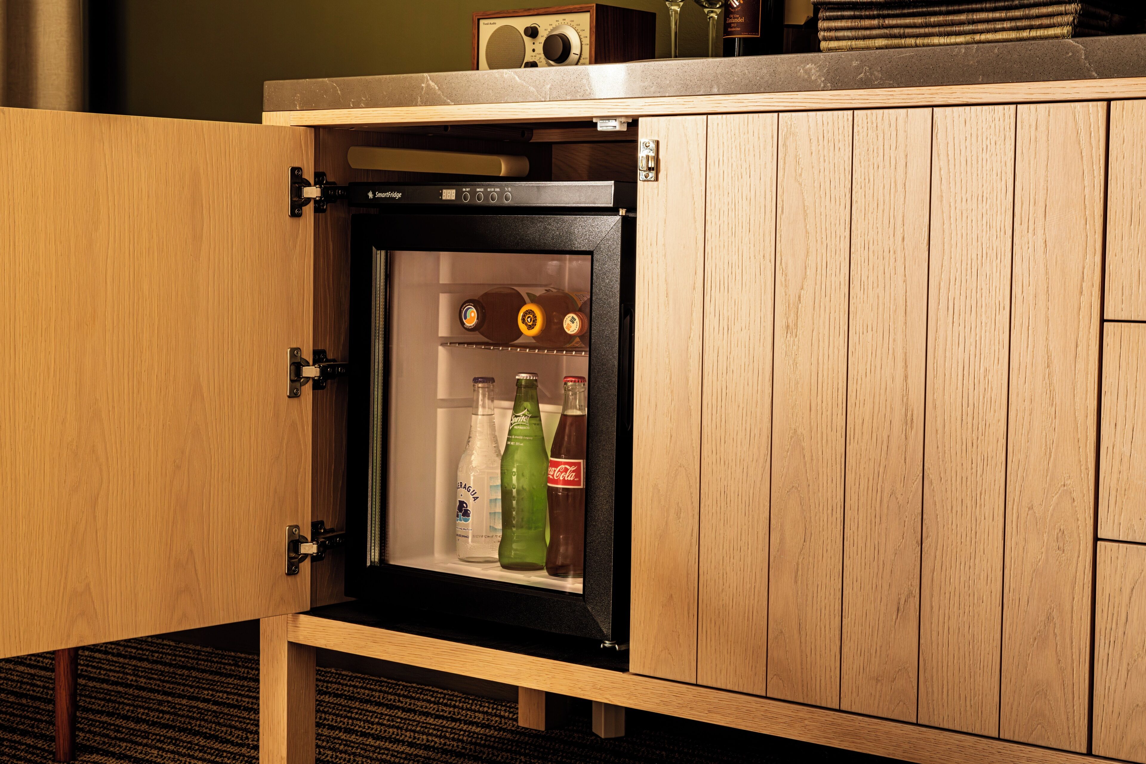 Un mini-bar équipé d’un réfrigérateur contenant des bouteilles de boissons.