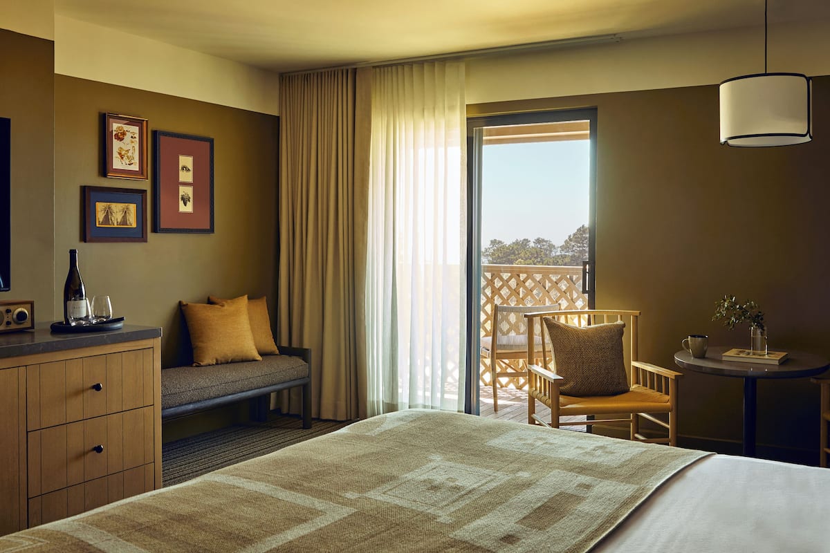 Une chambre d’hôtel équipée d’un lit, d’un bureau, d’une chaise, d’une petite table, d’un canapé, d’une télévision et d’un balcon avec vue.