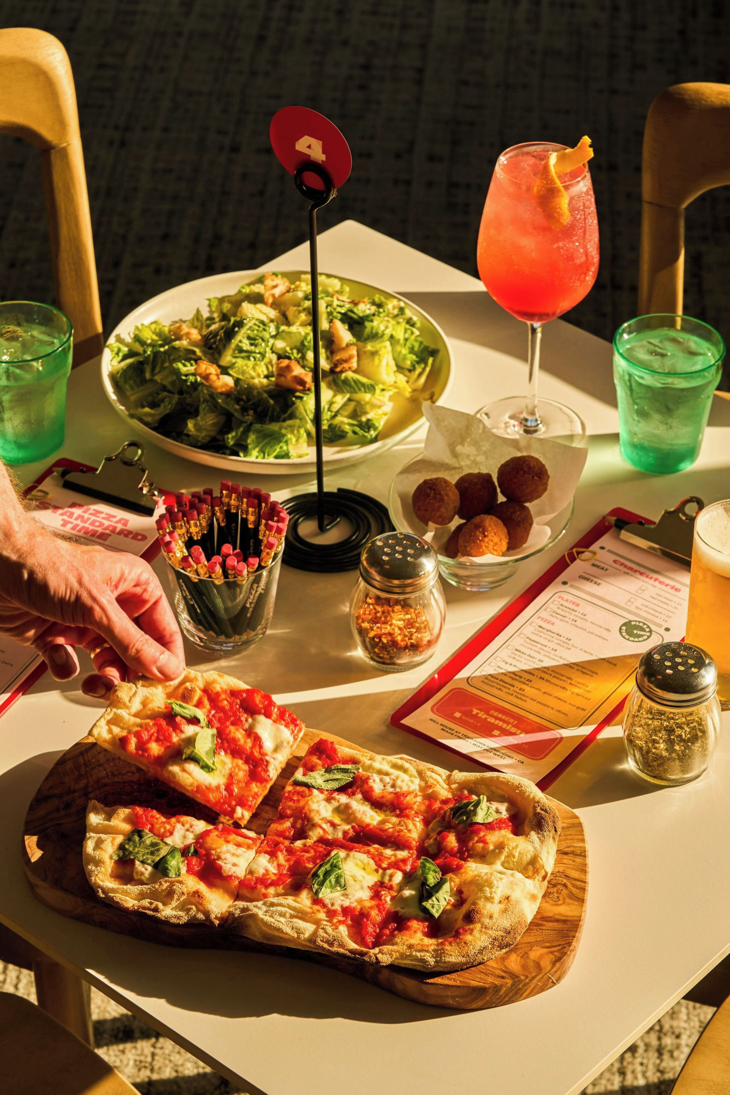 Ein Tisch mit Pizza, Salat, Getränken und Soßen.
