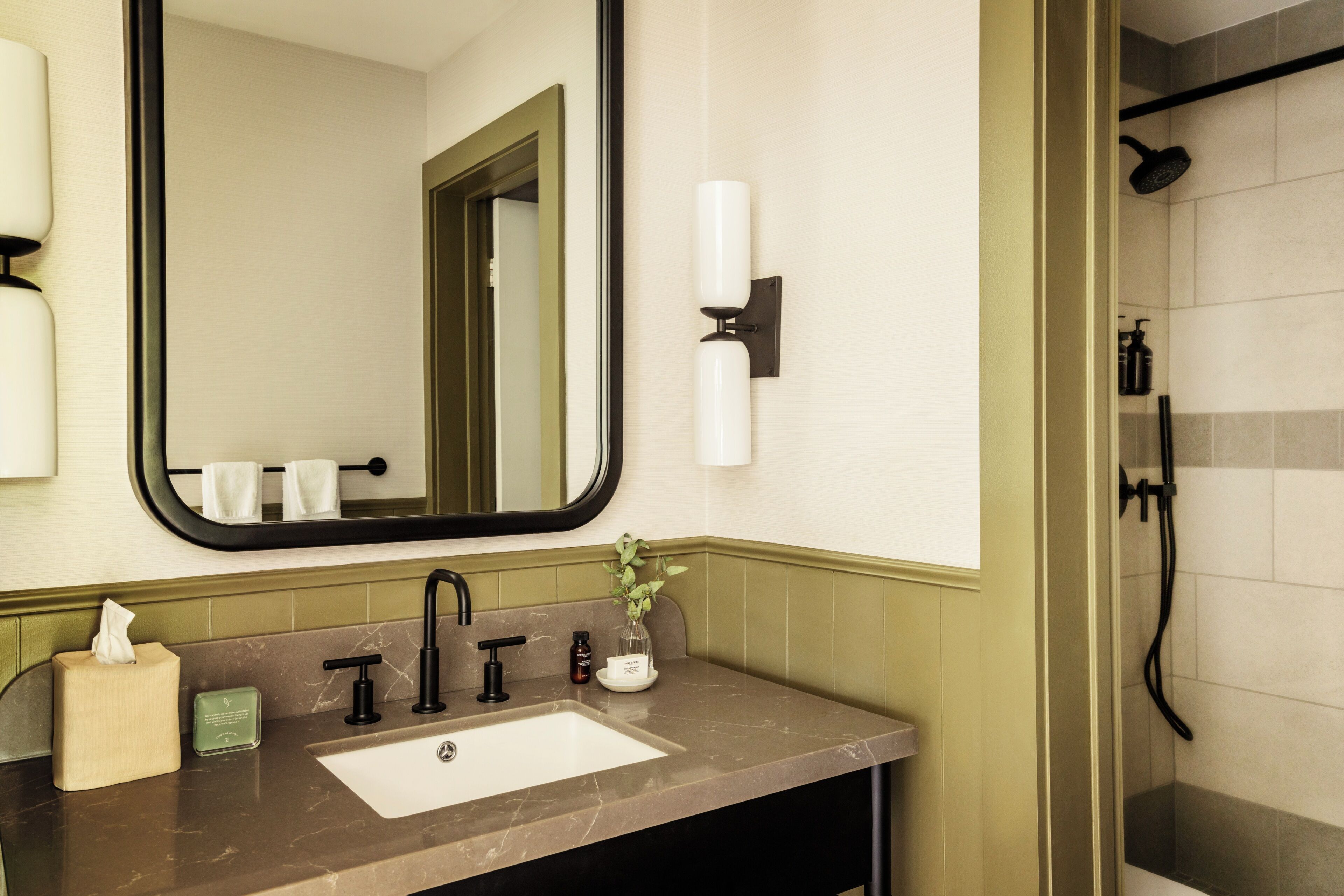 A bathroom with a sink, mirror, towel rack, and shower.