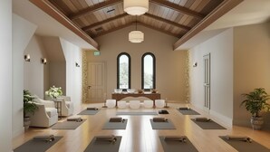 Un estudio de yoga con vigas de madera, ventanas amplias y una recepción.