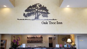 La zona de recepción del Oak Tree Inn, con un gran logotipo de un árbol, un mostrador de recepción y una foto colgada en la pared.