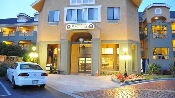 Un hotel con un letrero que dice 'Lobby', un coche estacionado al frente y una entrada bien iluminada.