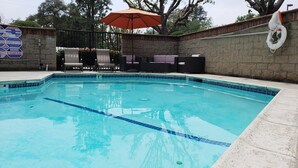 Una piscina con borde de azulejos, un flotador salvavidas y un cartel de advertencia.